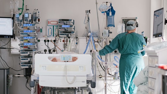 Eine Intensivpflegerin versorgt auf der Intensivstation einen an Covid-19 erkrankten Patienten. © dpa Foto: Ole Spata