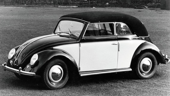 Ein schwarz-weißer VW Käfer steht auf einer Wiese. © Volkswagen AG 
