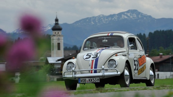 Ein VW Käfer fährt an einer Kirche vorbei. © Volkswagen AG 