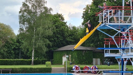 Eine Person springt in einem Kanu von einem 5-Meter-Turm in einem Schwimmbad. © NDR Foto: Theresa Möckel