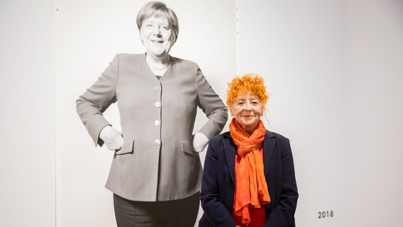 Herlinde Koelbl, Fotografin, steht bei einem Pressetermin zu ihrer Ausstellung "Angela Merkel Porträts 1991 · 2021" vor einem Porträt von Angela Merkel aus dem Jahr 2018. © dpa-Bildfunk Foto: Christoph Soeder