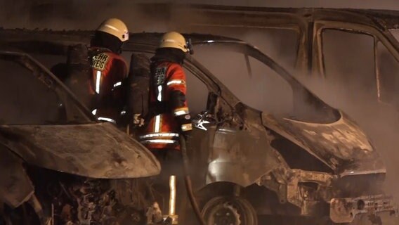 Feuerwehrleute stehen neben einem ausgebrannten Auto. © aktuell24 