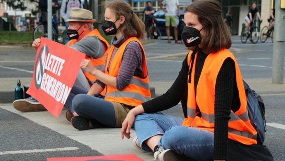 Menschen blockieren sitzend eine Straße. Menschen blockieren sitzend eine Straße. © Letzte Generation