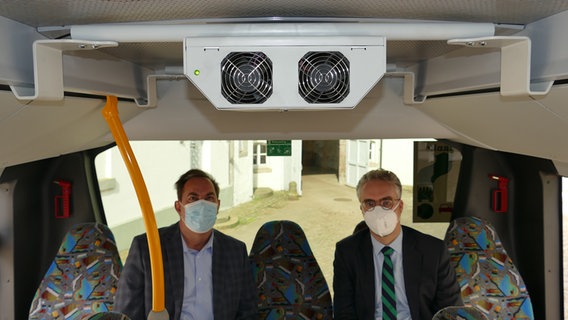 Stephan Heidenreich (Geschäftsführer der VLG, links) und Dr. Thomas Walter (Erster Kreisrat) sitzen unter einem Luftreinigungssystem in einem Linienbus. © Landkreis Gifhorn 