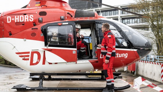 Michael John (re), Notfallsanitäter, und Nils Kunze-Szikszay, Notarzt, stehen an einem Hubschrauber der DRF-Luftrettung. © Swen Pförtner/dpa Foto: Swen Pförtner/dpa