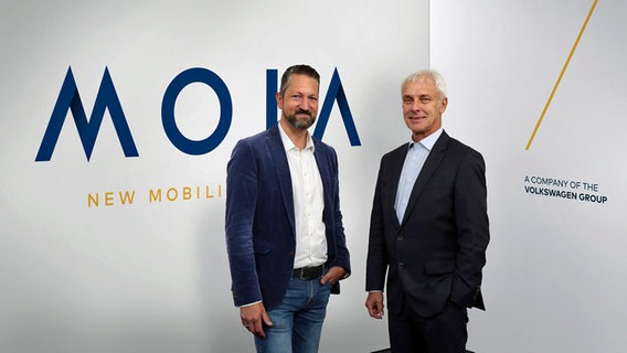 VW-Vorstandschef Matthias Müller und Ole Harms, Leiter der Mobilitätsmarke Moia, stehen vor dem Moia-Logo. © Volkswagen AG Foto: Matthias Leitzke
