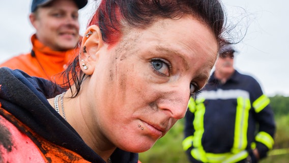 Eine Feuerwehrfrau mit Erde im Gesicht. © Julian Stratenschulte/dpa Foto: Julian Stratenschulte