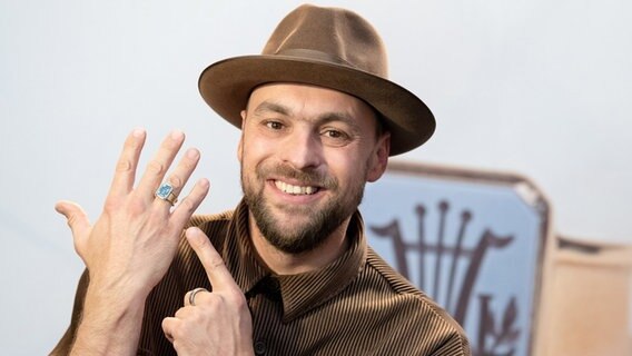 Max Mutzke, Musiker und Preisträger des Jahres 2021 des Paul-Lincke-Rings, zeigt nach der Preisverleihung seinen Ring. © Swen Pförtner/dpa 