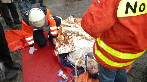 Der Rettungsdienst wickelt einen Mann in eine Decke ein. © NDR.de Foto: Jürgen Jenauer