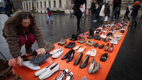 Symbolisch stehen 113 Paar Schuhe, stellvertretend für die 113 Frauen, die im Jahr 2021 von ihren (Ex-)Partnern getötet wurden, auf den Braunschweiger Schlossplatz. © dpa-Bildfunk Foto: Friso Gentsch