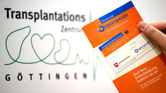 Eine Broschüre zur Organspende wird vor einem Schild "Transplantationszentrum" in die der Hand gehalten. © picture alliance/Swen Pförtner/dpa Foto: Swen Pförtner