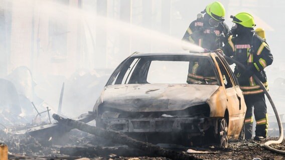 Zwei Feuerwehrmänner an einem ausgebranntem Auto. © HannoverReporter Foto: HannoverReporter