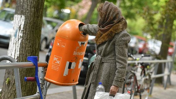 Eine Frau sucht in einem öffentlichen Mülleimer nach Pfandflaschen. © dpa/picture alliance Foto: Bildagentur-online/Schoening