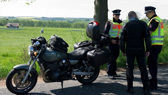 Zwei Polizisten kontrollieren einen Motorradfahrer. © picture alliance / dpa | Swen Pförtner Foto: Swen Pförtner
