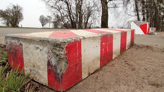 Auf einer Straße steht ein Stück rot-weiß-gestreifter Beton. © NDR Foto: Tino Nowitzki