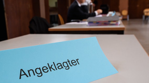In einem Gerichtssaal ist auf einem Tisch das Schild "Angeklagter" aufgestellt. © picture alliance/dpa/Swen Pförtner Foto: Swen Pförtner