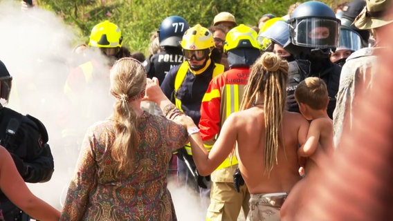 Teilnehmende des "Rainbow Gathering" stehen Einsatzkräften gegenüber. © NDR 