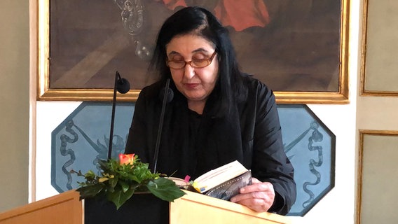 Schriftstellerin Emine Sevgi Özdamar steht an einem Pult und liest aus einem Buch vor. © NDR Foto: Ute Andres