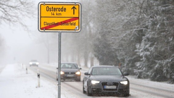 Autos fahren am Ortseingang von Clausthal-Zellerfeld über schneebedeckte Straßen. © dpa Foto: Frank Neuendorf