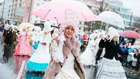Eine Frau läuft verkleidet und mit Regenschirm beim Karnevalsumzug mit. © NDR Foto: Julius Matuschik