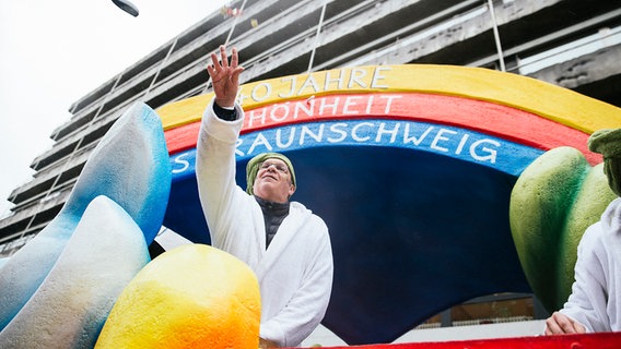 Ein Mann wirft Bonbons vom Karnevalswagen. © NDR Foto: Julius Matuschik