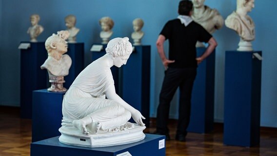 Römische Skulpturen der ältesten privaten Sammlung in Göttingen sind in einem Raum ausgestellt, im Hintergrund ist ein Besucher zu sehen. © dpa Foto: Swen Pförtner