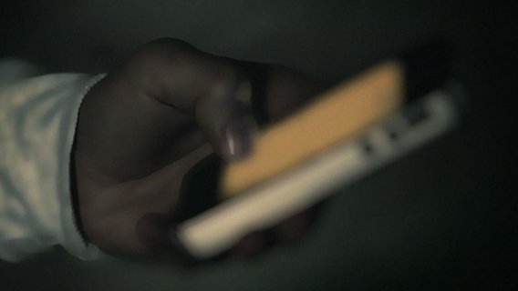 Eine Hand tippt auf ein Smartphone.  