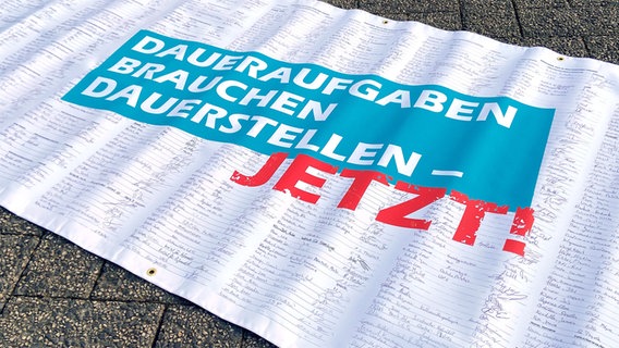 Bei einer Demo zu Tarifverträgen für Uni-Beschäftigte in Göttingen steht auf einem Banner voller Unterschriften "Daueraufgaben brauchen Dauerstellen - jetzt!". © NDR Foto: Bärbel Wiethoff