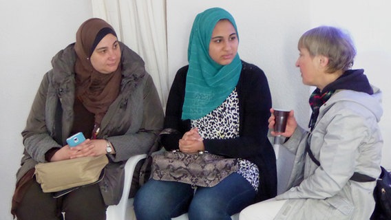 Zwei Frauen mit Kopftuch sprechen mit einer älteren Dame. © NDR Foto: Sebastian Deliga