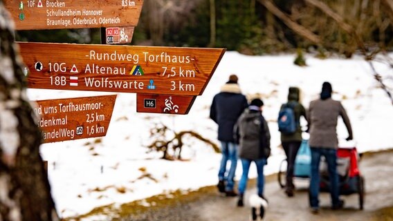 Eine Familie geht im Harz an einem Wegweiser vorbei. © picture alliance/dpa/Swen Pförtner Foto: Swen Pförtner