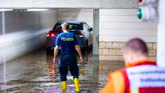 Einsatzkräfte der Feuerwehr arbeiten in der Nacht in einer mit Regenwasser vollgelaufenen Tiefgarage in Braunschweig. © dpa Foto: Moritz Frankenberg