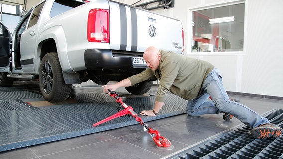 Der VW-Kunde Stefan Ader kniet hinter seinem VW Amarok. © NDR Foto: Björn Siebke