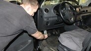Fahrzeugtechniker Daniel Wiegmann zapft im Fussraum eines VW Amarok Daten aus dem Steuergerät ab. © NDR Foto: Carmen Woisczyk