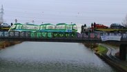 Klimaaktivsten haben einen Autozug mit Fahrzeugen von Volkswagen auf einer Brücke gekapert und mit Transparenten zu einer Straßenbahn verkleidet. © verkehrswendestadt.de 