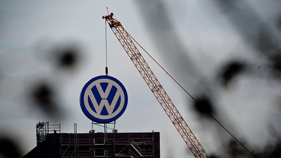 Ein Kran hängt über einem VW-Logo. © dpa - Bildfunk Foto: Peter Steffen
