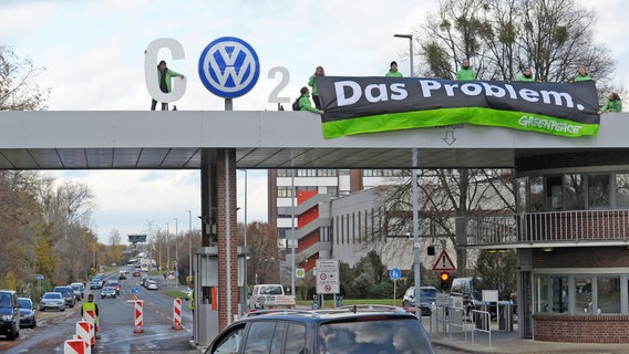 Mehrere Greenpeace-Aktivisten stehen auf dem Eingang der VW-Zentrale in Wolfsburg und halten ein Banner mit der Aufschrift: "Das Problem" hoch. © dpa - Bildfunk Foto: Peter Steffen
