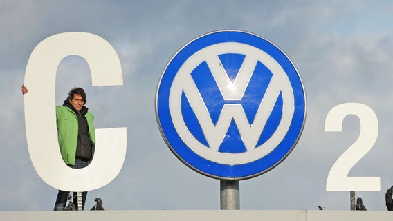 Ein Greenpeace-Aktivisten steht auf dem Eingang der VW-Zentrale in Wolfsburg. Das VW-Logo haben sie mit einem C und einer 2 erweitert (CO2). © dpa - Bildfunk Foto: Peter Steffen