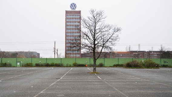Vor dem Verwaltungshochhaus der Volkswagen AG in Wolfsburg sind Schneeflocken und ein leerer Parkplatz zu sehen. © dpa - Bildfunk Foto: Julian Stratenschulte