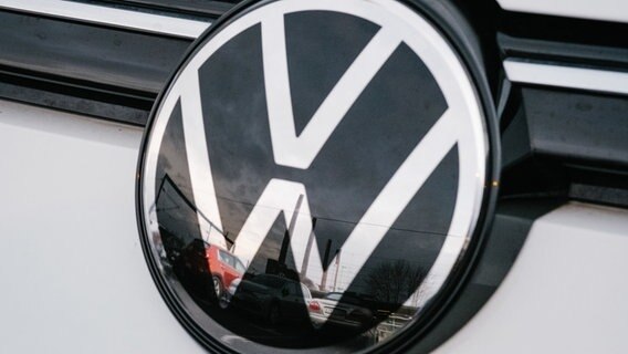Das Volkswagenwerk spiegelt sich in einem VW Logo. © Ole Spata/dpa Foto: Ole Spata
