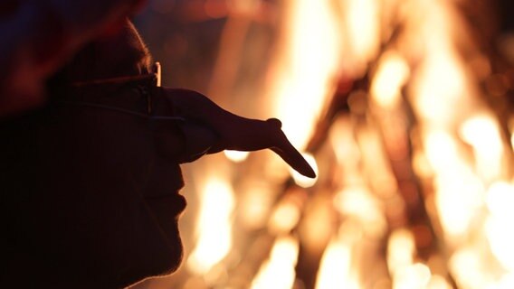 Die Silhouette einer Hexe ist vor einem Feuer beim traditionellen Walpurgisfest. © dpa-Bildfunk Foto: Jens Wolf