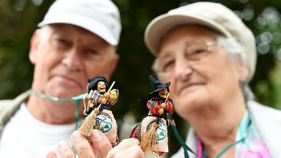 Zwei Wanderer halten kleine Hexenfiguren in den Händen. © dpa-Bildfunk Foto: Swen Pförtner