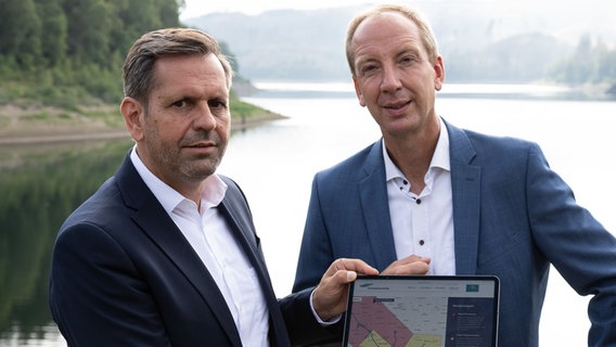 Olaf Lies (SPD, l), Umweltminister in Niedersachsen, und Christoph Donner, Technischer Geschäftsführer der Harzwasserwerke, stehen mit einem Tablet bei der Vorstellung einer Wasserampel der Harzwasserwerke an der Sösetalsperre im Harz. © Swen Pförtner/dpa Foto: Swen Pförtner