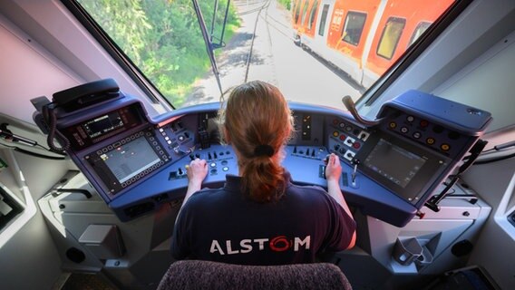 Ein Mitarbeiter des Zugherstellers Alstom steuert einen Wasserstoffzug. © Julian Stratenschulte/dpa Foto: Julian Stratenschulte