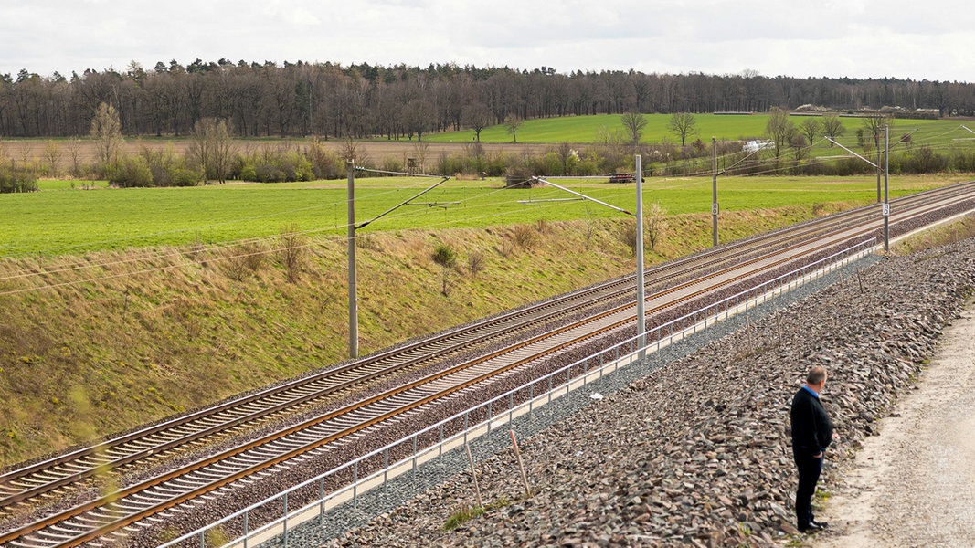 Ein Mann steht einsam an einem zweigleisigen Abschnitt der Bahnstrecke 