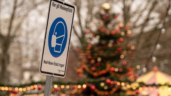 Ein Schild auf einem Weihnachtsmarkt weißt auf die Maskenpflicht hin. © dpa-Bildfunk Foto: Swen Pförtner