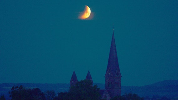 Der Mond steht über einem Kirchturm. © NDR Foto: Konrad Horn
