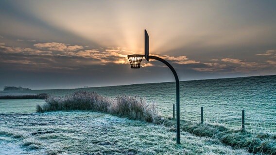 Ein Basketballkorb über einer vereisten Wiese. © NDR Foto: Sascha Meinardus