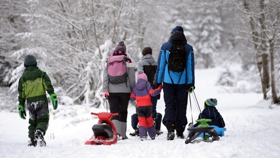 Eine Familie zieht Schlitten durch den verschneiten Harz. © picture alliance Foto: Swen Pförtner