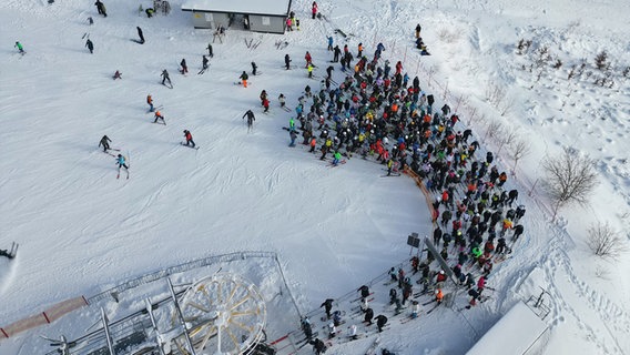 Wintersportbesucher stehen am Skilift am Wurmberg an (Luftaufnahme mit Drohne). © Matthias Bein/dpa Foto: Matthias Bein/dpa