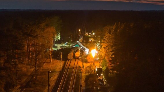 Leiferde: Beschädigte Waggons stehen und liegen auf dem Bahndamm, während Gas aus einem der Waggons kontrolliert abgefackelt wird. © dpa-Bildfunk Foto: Philipp Schulze